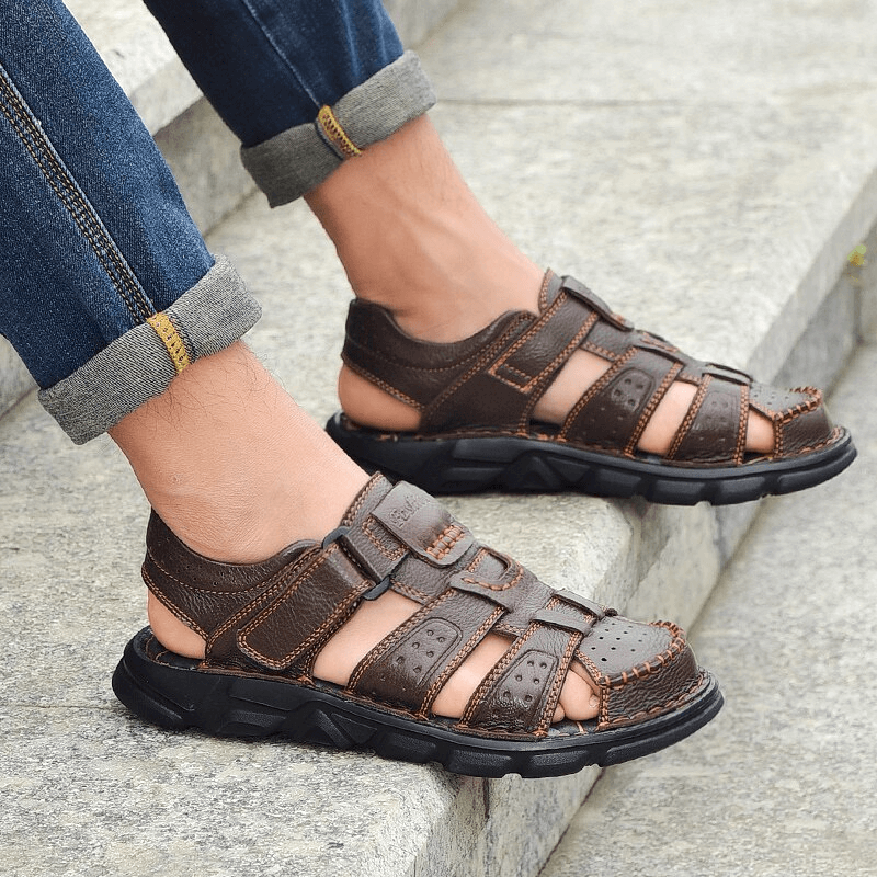 Men's genuine leather trekking sandals with soft soles and anti-collision toes, worn with jeans, on a stone staircase.